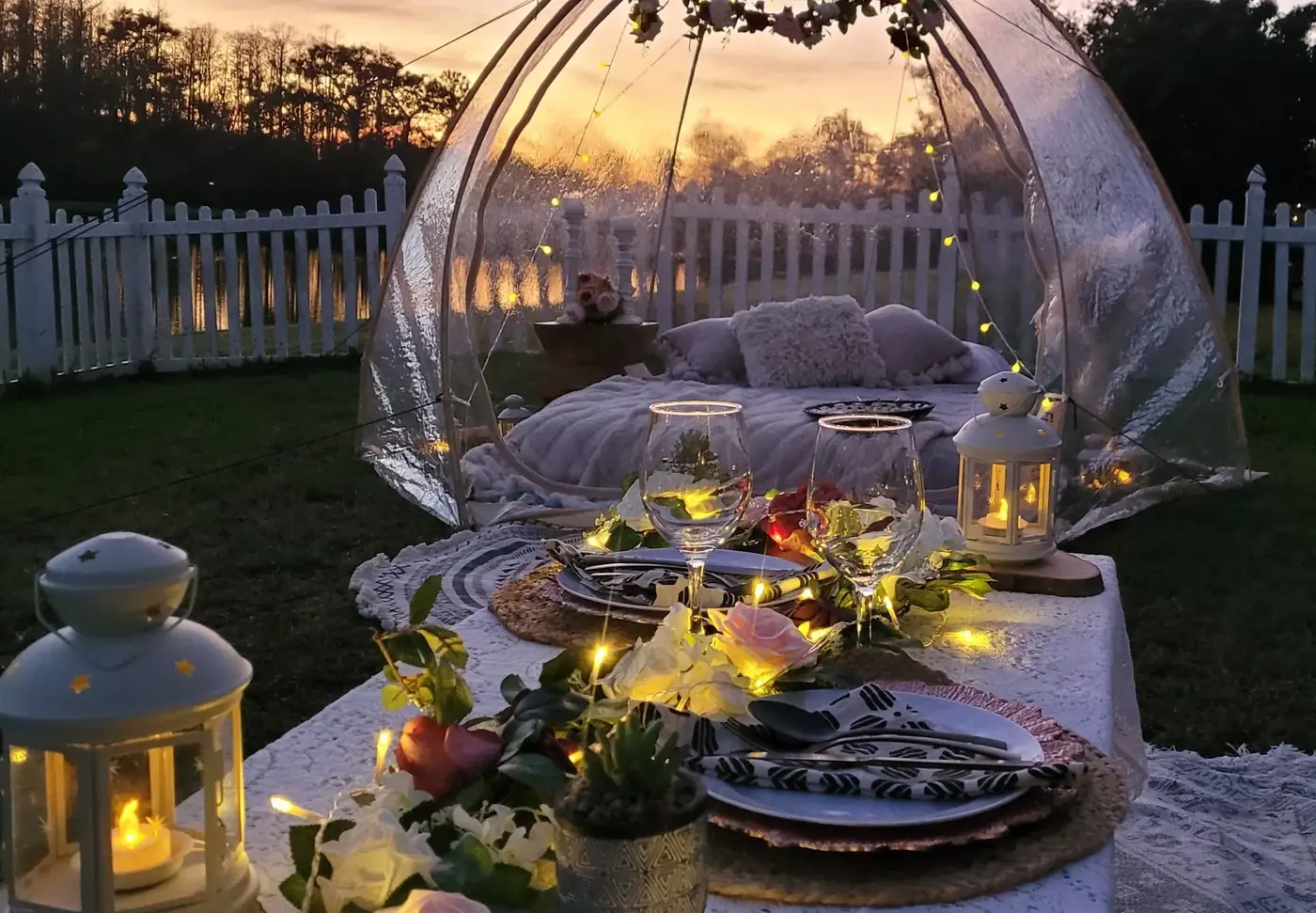 Adults enjoying a sunset date-night setup in an outdoor bubble tent by In Your Dreams Sleepovers